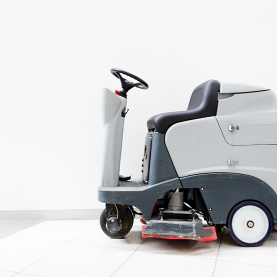 Riding cleaning machine against a white wall 